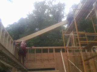 Carpenter raising a rafter beam on a new second story frame in Platteville