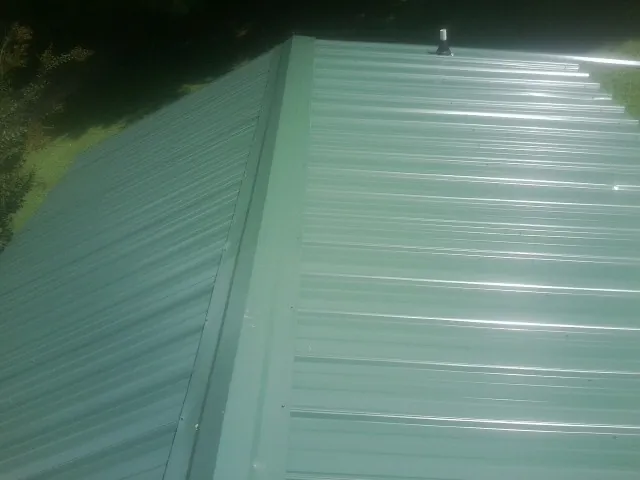New green metal panels meeting at the ridge of a roof — Flat Roof Repair work by our crew in Platteville