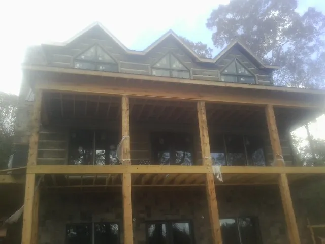 Dormers and porch framing on a large log home under construction — Roof Coating work by our crew in Platteville
