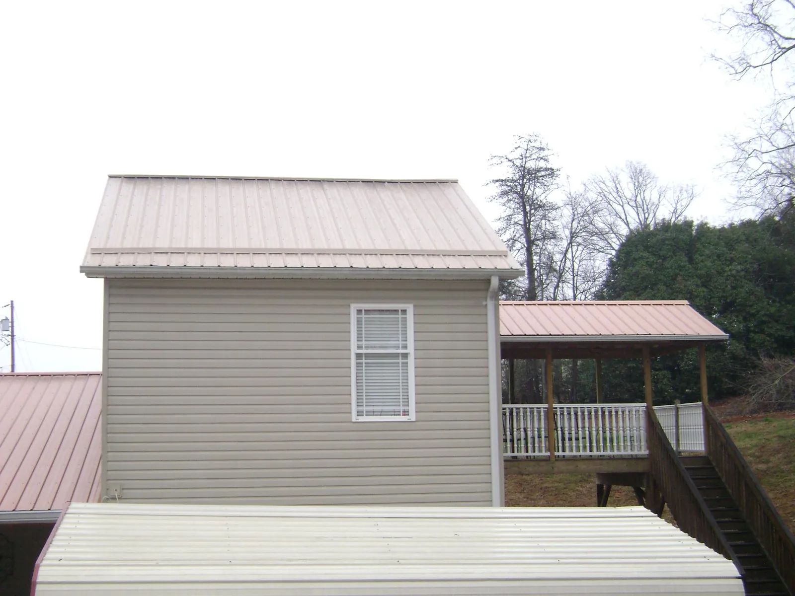 Tan metal roofs on a two story addition and attached porch, from a Roof Replacement job in Platteville