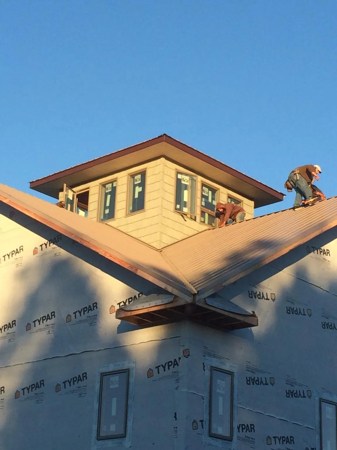 Roofers working around a rooftop cupola on a new metal roof at sunset — Roof Waterproofing in Platteville by Roofing Brothers